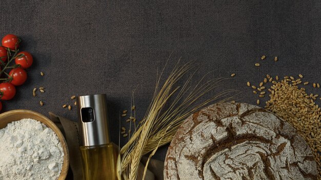 frisches dunkles Brot auf dunklem Hintergrund mit Olivenöl im Spender frische Tomaten und Holzschale
