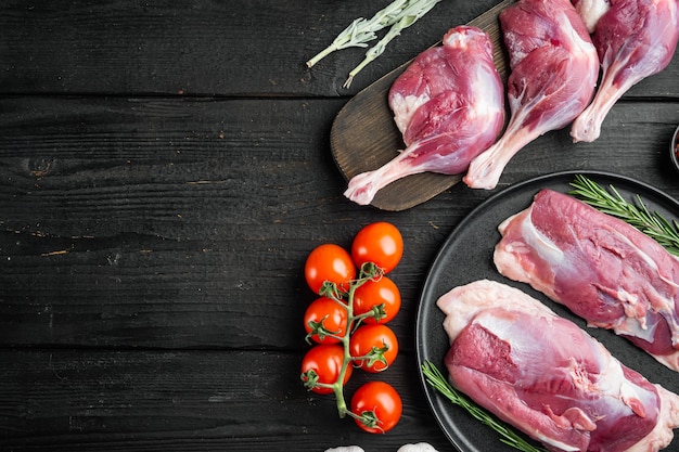 Frisches Entenbein und Brustfleisch mit Kräutern und Zutaten auf schwarzem Holztisch