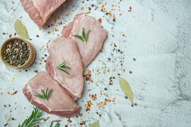 Frisches Fleisch mit Gewürzen auf hellem Hintergrund. In Scheiben geschnittene frische Steaks. Platz für Text.