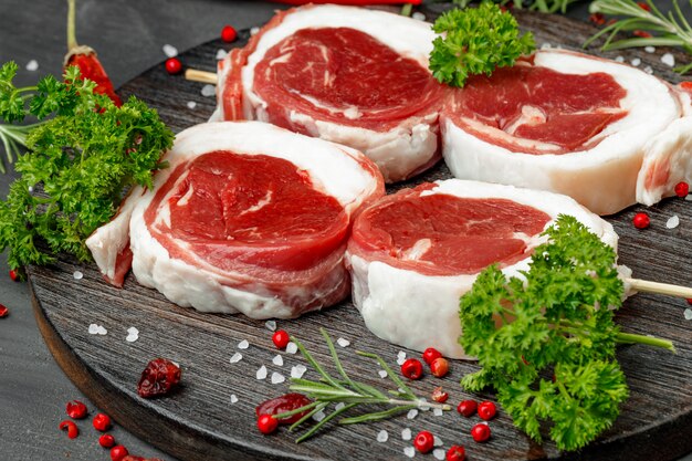 Frisches Fleisch mit Zutaten zum Kochen auf dunklem Hintergrund