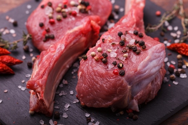 Frisches Fleisch vom Knochensteak mit Gewürzen und Kräutern