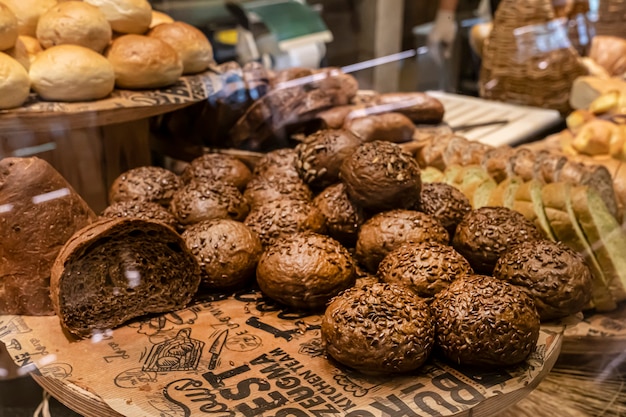 Frisches Gebäck in der Bäckerei schwarze runde Brötchen mit Getreide bestreut frisches Gebäck braune kleine Burger