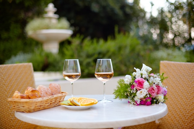 Frisches Gebäck, Obstteller, Gläser mit Roséwein und ein Strauß schöner Blumen