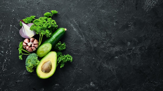 Frisches Gemüse auf schwarzem Hintergrund Avocados Tomaten Knoblauch Petersilie Paprika Ansicht von oben Freier Platz für Ihren Text