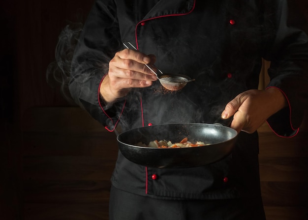 Frisches Gemüse kochen Der Koch gibt Paprika in eine dampfend heiße Pfanne. Die Idee der europäischen Küche für ein Hotel mit Werbefläche