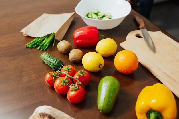 Frisches gemüse obstmesser und schneidebrett zum kochen abendessen auf holz