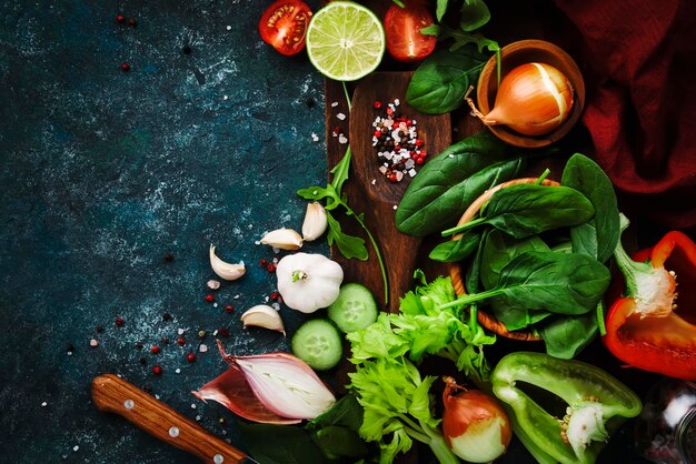 Frisches gesundes Essen kochen oder Salatzutaten auf dunklem Hintergrund mit rustikalem Holzbrett Diät- oder vegetarisches Lebensmittelkonzept Kopierraum von oben