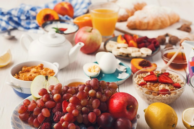 Frisches gesundes Frühstück mit Fruchtnahaufnahme. Schüssel mit Trauben, Beeren und Apfel mit Frühstückssortiment auf Holztisch