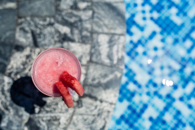 Frisches Glas des Wassermelone Smoothiegetränks, das nahen Swimmingpool steht