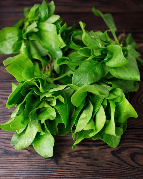 Frisches Grün auf einem braunen Holztisch Spinat Bio-Lebensmittel Zubereitung von veganem Essen Ernte von Kräutern