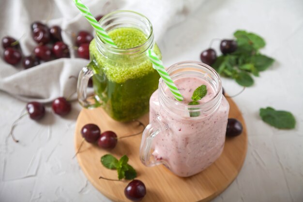 Frisches Grün und süße Kirschsmoothies, süße Kirschbeeren und Leinenserviette