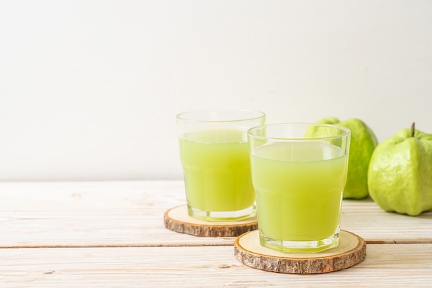 frisches Guavensaftglas mit frischen Guavenfrüchten auf Holztisch