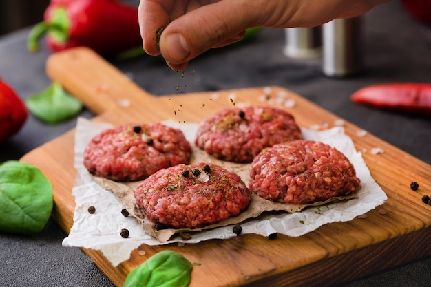 Frisches Hackfleischbällchen-Lebensmittelfoto mit Hand, die Gewürze Meersalz gießt Kochprozess