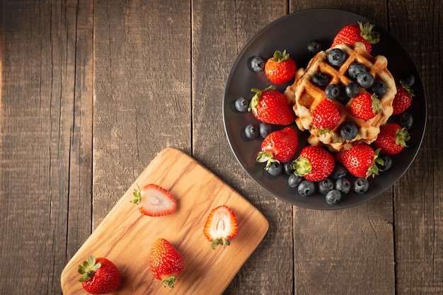 Frisches hausgemachtes Essen aus belgischen Beerenwaffeln mit Honig-Erdbeer-Heidelbeere und Sirup