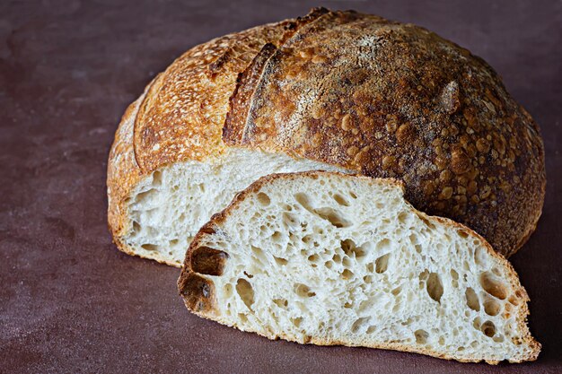 Frisches hausgemachtes Sauerteigbrot mit Vollkornmehl auf braunem Hintergrund. Gesundes Essen.