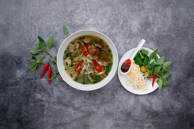 Frisches heißes rindfleisch pho mit salatblättern serviert in einer schüssel isoliert auf dunkelgrauem hintergrund draufsicht auf japanisches essen