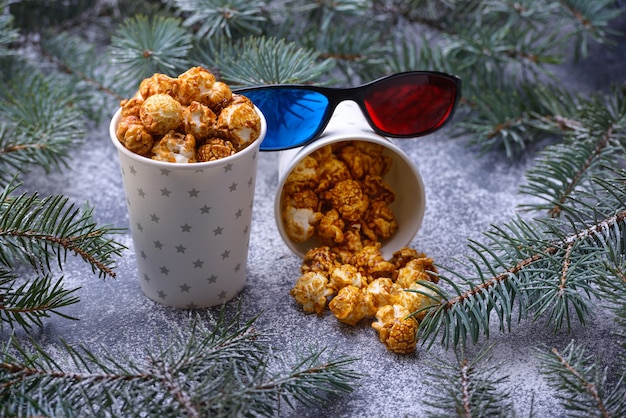 Frisches knuspriges hausgemachtes Popcorn im Pappbecher neben mit Weihnachtsbaum und Dekor