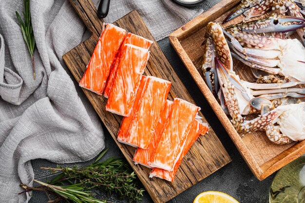 Frisches Krabbenfleisch Stick Surimi mit blauem Schwimmkrabbenset, auf grauem Hintergrund, Draufsicht flach