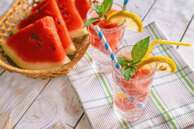 Frisches kühles Sommergetränk mit Wassermelonenscheiben, Minze und Zitrone auf einem hölzernen Hintergrund,