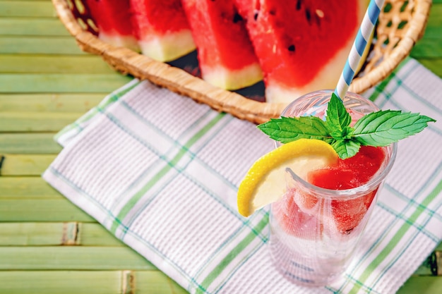 Frisches kühles Sommergetränk mit Wassermelonenscheiben, Minze und Zitrone auf einem hölzernen Hintergrund