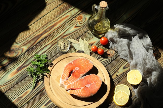 Frisches Lachssteak mit Zutaten auf dunklem Holzhintergrund