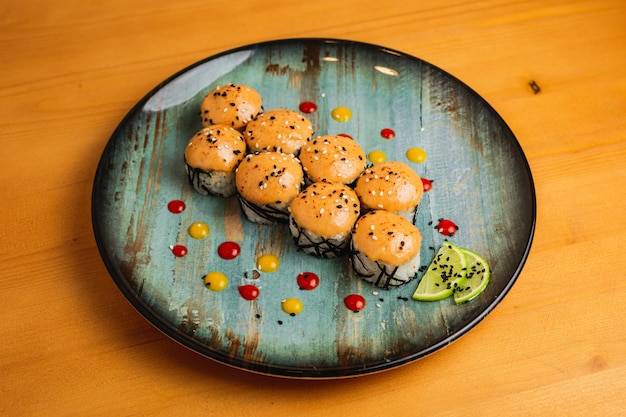 Frisches Maki bedeckt mit Orangensauce auf einem blauen Teller