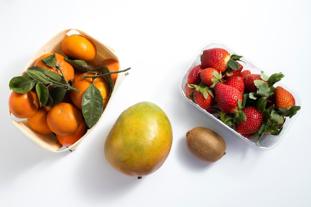 Frisches Obst Mango Erdbeeren Mandarinen Kiwi auf weißem Hintergrund Draufsicht flach liegen