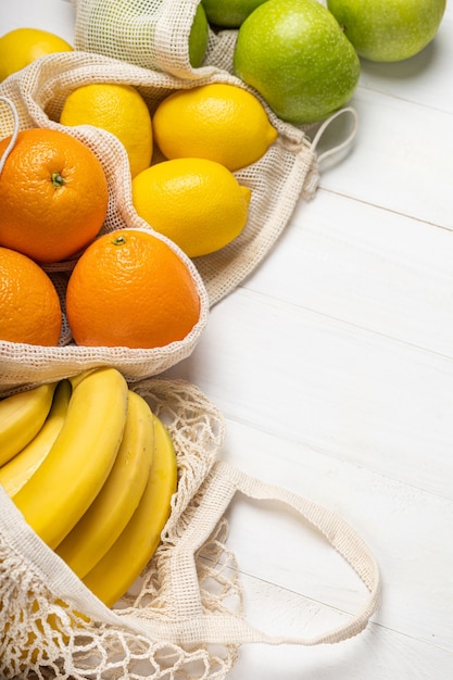 Frisches Obst, Äpfel, Bananen, Orangen und Zitronen in umweltfreundlichen Beuteln grenzen an