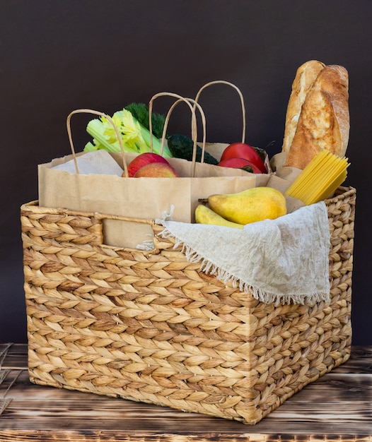 Foto frisches öko-bio-gemüse, gemüse und obst, müsli und nudeln in einem weidenkorb. lieferung oder spende eines ökologischen farm food-konzepts