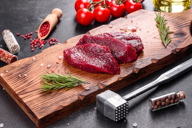 Frisches Raw Beef Steak Mignon, mit Salz, Pfefferkörnern, Thymian, Tomaten. Rohes frisches Marmorfleisch Steak und Gewürze