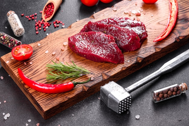 Frisches Raw Beef Steak Mignon, mit Salz, Pfefferkörnern, Thymian, Tomaten. Rohes frisches Marmorfleisch Steak und Gewürze