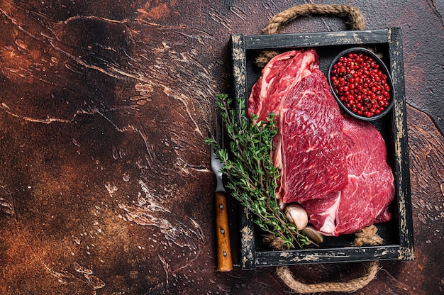 Foto frisches raw chuck eye roll rindersteak in einem holztablett mit kräutern