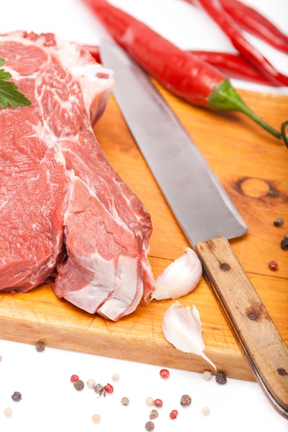 Frisches Rindfleisch vom Fleisch mit Knochen auf hölzernen Gewürzen und Messer