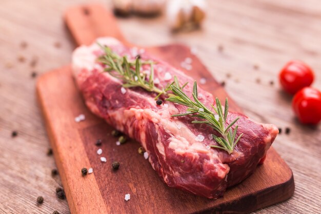 Frisches rohes Fleisch für Steak auf Holzschneidebrett, Nahaufnahme.