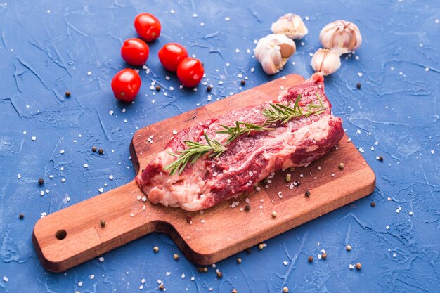 Frisches rohes Fleisch für Steak auf Holzschneidebrett.