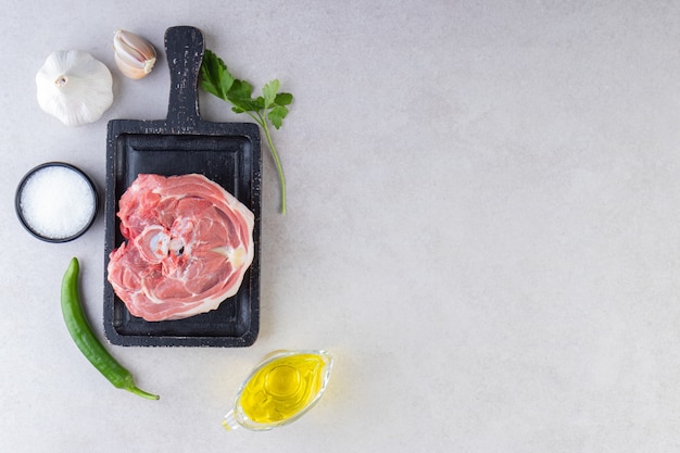 Frisches rohes Fleisch mit Gemüse und Pfefferkörnern auf Steintisch gelegt.