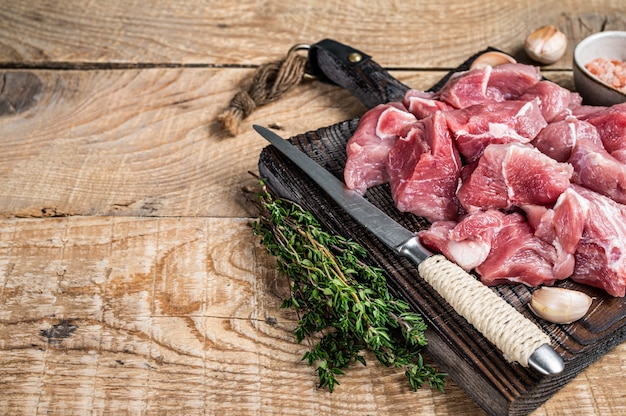 Frisches, rohes, gewürfeltes Schweinefleisch mit Gewürzen auf einem hölzernen Metzgerbrett