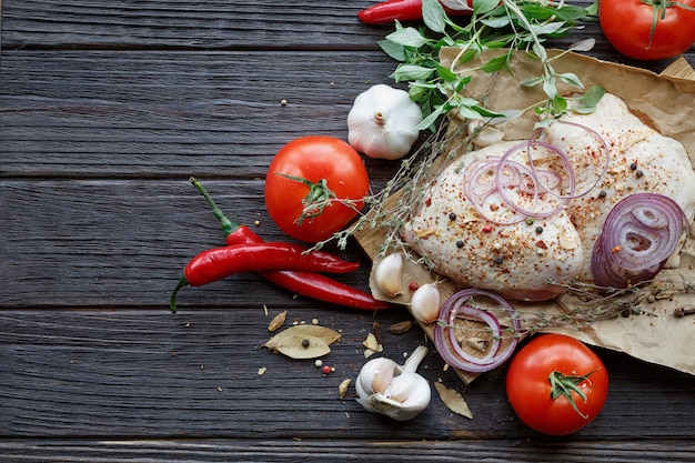 Frisches rohes Huhn mit Kräutern, Knoblauch, Zwiebeln, Tomaten und Chili