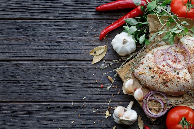 Frisches rohes Huhn mit Kräutern, Knoblauch, Zwiebeln, Tomaten und Chili