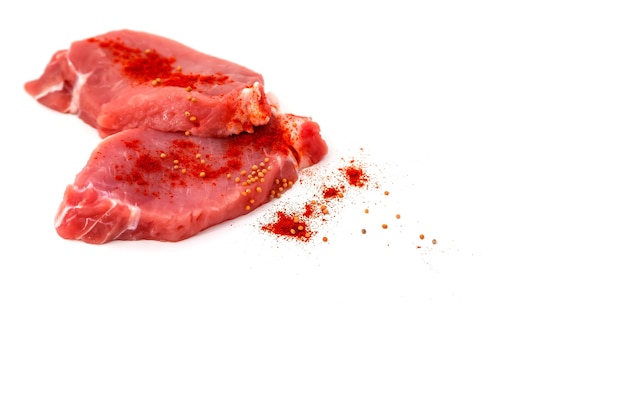 Frisches rohes Rindersteak isoliert auf weißem Hintergrund. Mit Senf und rotem Cayenne-Chili gewürztes Schweinekotelett ist kochfertig. Zwei Stück Fleisch. Konzept der Kochkunst. Platz für eine Inschrift oder ein Logo
