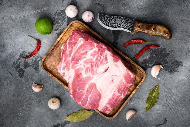 Frisches rohes Schweinehals-Fleisch-Set, mit Zutaten und Kräutern, auf grauem Steintischhintergrund, Draufsicht flach