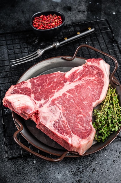 Frisches rohes T-Bone-Marmor-Rindfleisch Steak auf einem Stahlplatt Schwarzer Hintergrund Top-View