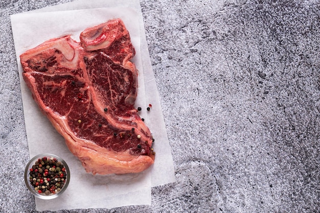 Frisches rohes Tbone-Steak auf grauem Steinhintergrund