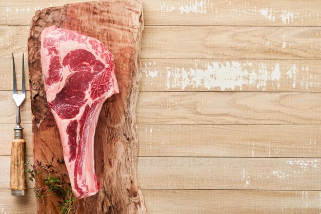 Frisches rohes Tomahawk-Steak Trocken gereiftes rohes Tomahawk-Rindsteak mit Kräutern und Salz auf altem Holzhintergrund Vorbereitung zum Grillen Draufsicht und Kopierbereich