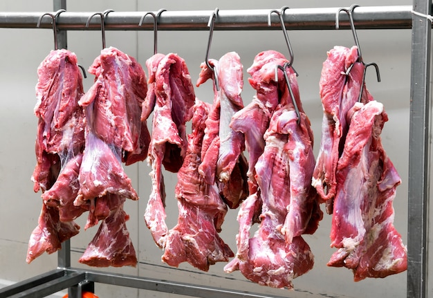 Frisches rotes Fleisch hängt an Metallhaken