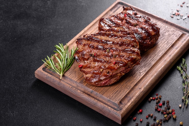 Frisches saftiges köstliches Rindersteak auf Holztisch. Fleischgericht mit Gewürzen und Kräutern