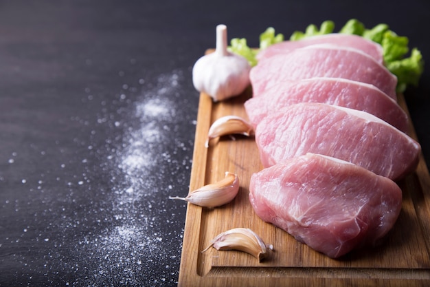 Frisches Schweinefleisch auf Holzbrett mit Gewürzen. Rohes Fleisch.