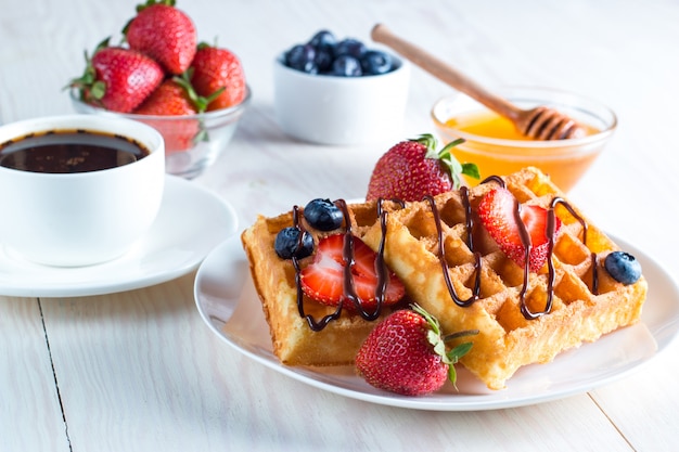 Frisches selbst gemachtes Lebensmittel von belgischen Waffeln der Beere mit Honig, Schokolade, Erdbeere, Blaubeere, Ahornsirup und Creme. Gesundes Nachtischfrühstückskonzept mit Saft