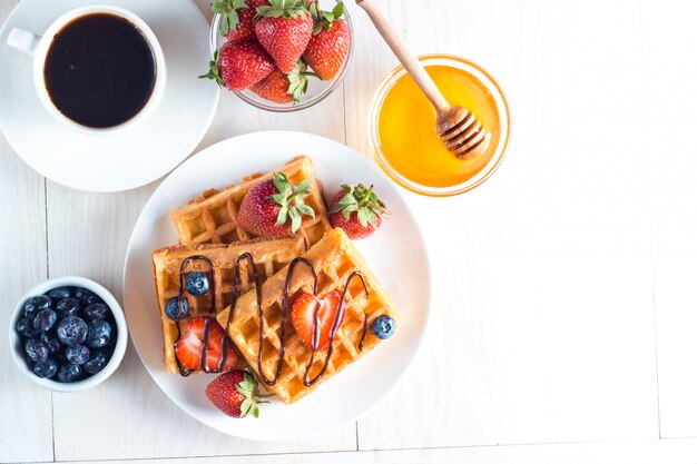 Frisches selbst gemachtes Lebensmittel von belgischen Waffeln der Beere mit Honig, Schokolade, Erdbeere, Blaubeere, Ahornsirup und Creme. Gesundes Nachtischfrühstückskonzept mit Saft