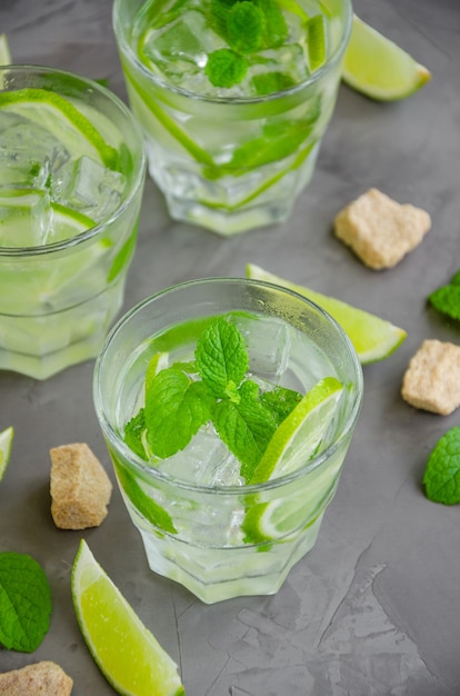 Frisches Sommer-Mojito-Getränk mit Limettenscheiben, Minze, Eiswürfeln und braunem Zucker in einem Glas